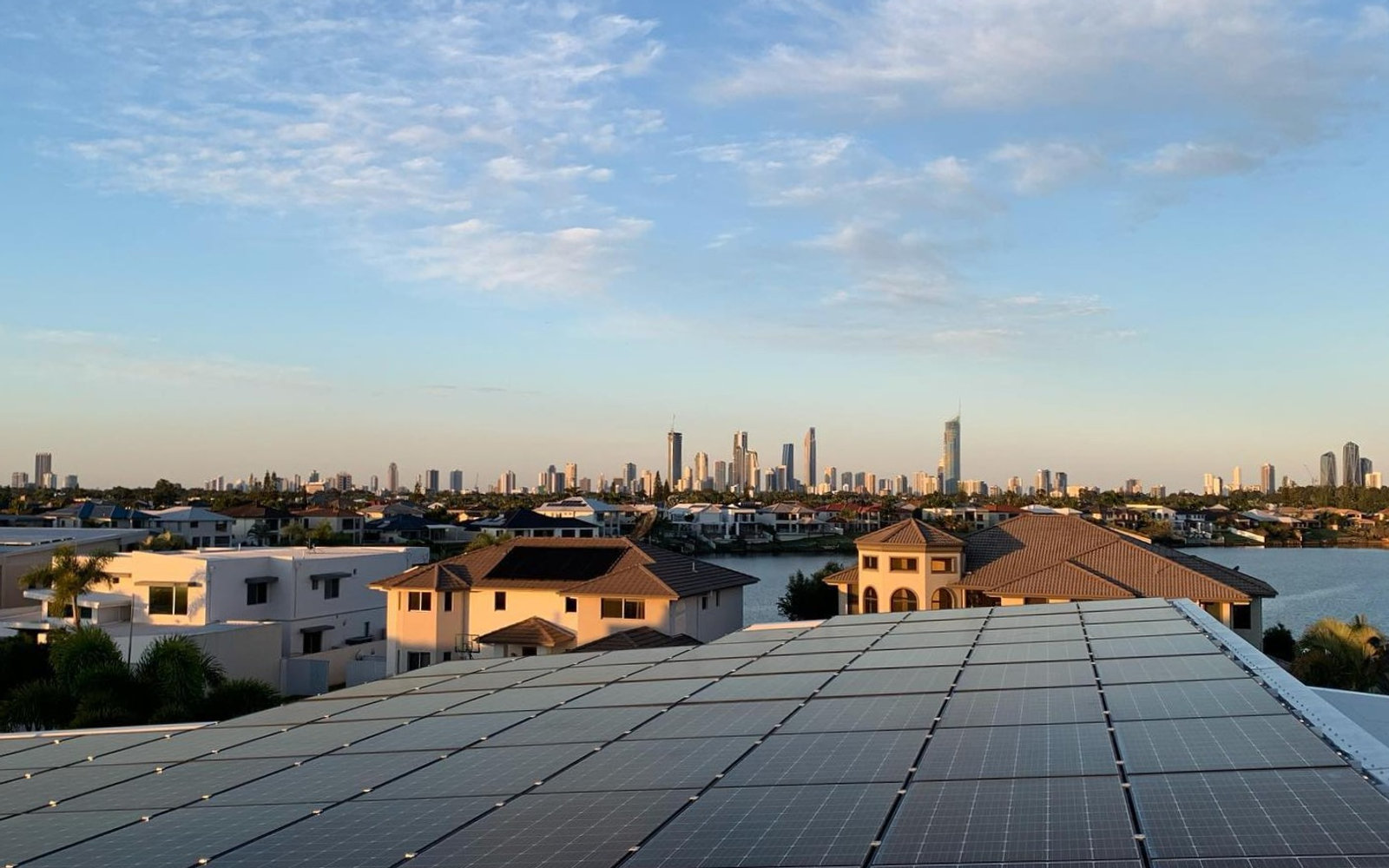 Rooftop solar install overlooking the Gold Coast skyline at golden hour
